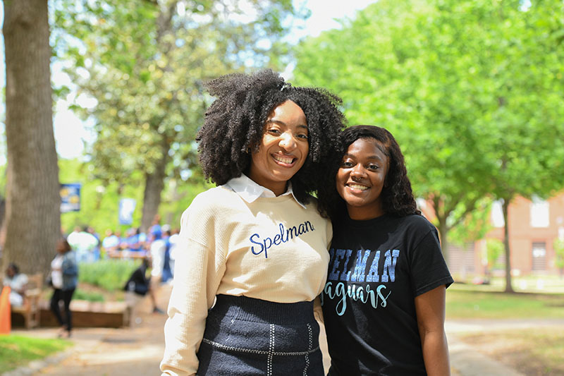 Two students smiling and hugging each other.